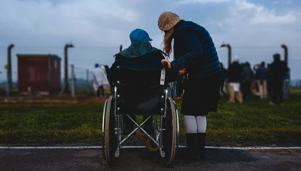 woman standing near person in wheelchair near green grass field